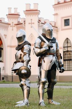 Two knights in armor on the background of the medieval Kossovsky castle.A medieval concept.Metallic texture.