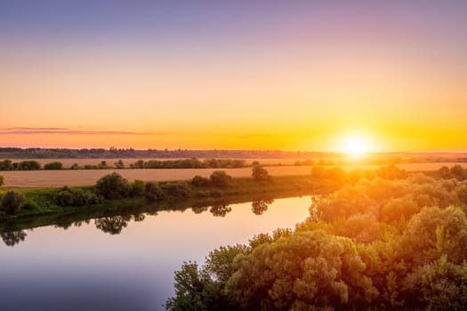 A sunset or sunrise scene over a lake or river with skies reflecting in the water on a summer evening or morning. Landscape.