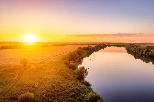 A sunset or sunrise scene over a lake or river with skies reflecting in the water on a summer evening or morning. Landscape.