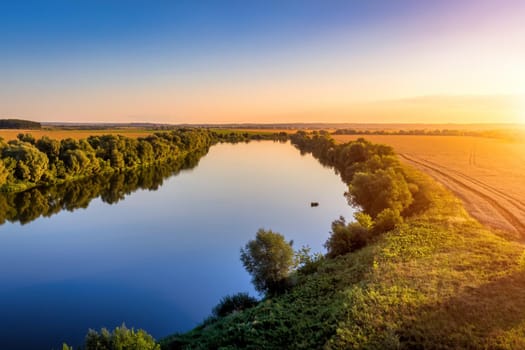 A sunset or sunrise scene over a lake or river with skies reflecting in the water on a summer evening or morning. Landscape.