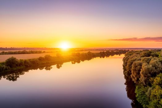 A sunset or sunrise scene over a lake or river with skies reflecting in the water on a summer evening or morning. Landscape.