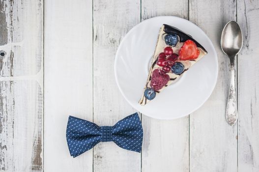 Mix berry slice cake on white plate with bow tie on old wood background Happy Father's Day.