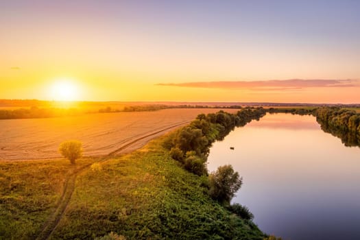 A sunset or sunrise scene over a lake or river with skies reflecting in the water on a summer evening or morning. Landscape.