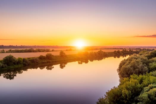 A sunset or sunrise scene over a lake or river with skies reflecting in the water on a summer evening or morning. Landscape.