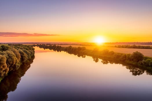 A sunset or sunrise scene over a lake or river with skies reflecting in the water on a summer evening or morning. Landscape.