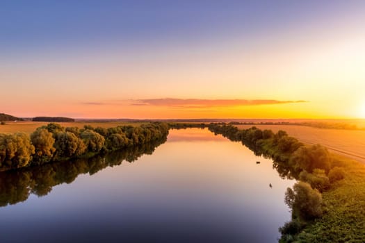 A sunset or sunrise scene over a lake or river with skies reflecting in the water on a summer evening or morning. Landscape.