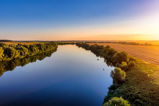 A sunset or sunrise scene over a lake or river with skies reflecting in the water on a summer evening or morning. Landscape.