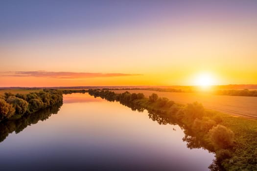 A sunset or sunrise scene over a lake or river with skies reflecting in the water on a summer evening or morning. Landscape.