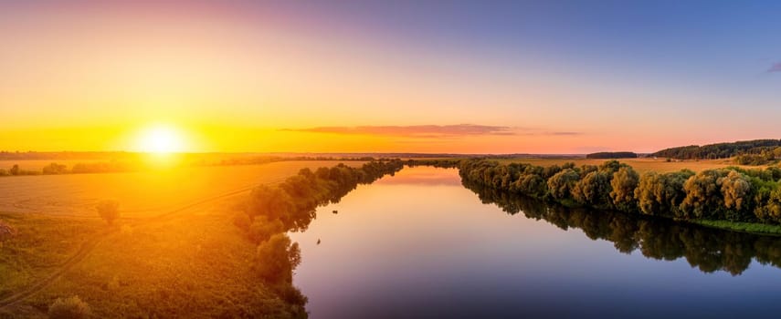 A sunset or sunrise scene over a lake or river with skies reflecting in the water on a summer evening or morning. Panorama.