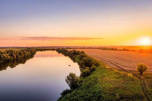 A sunset or sunrise scene over a lake or river with skies reflecting in the water on a summer evening or morning. Landscape.