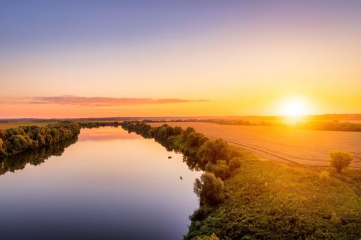 A sunset or sunrise scene over a lake or river with skies reflecting in the water on a summer evening or morning. Landscape.