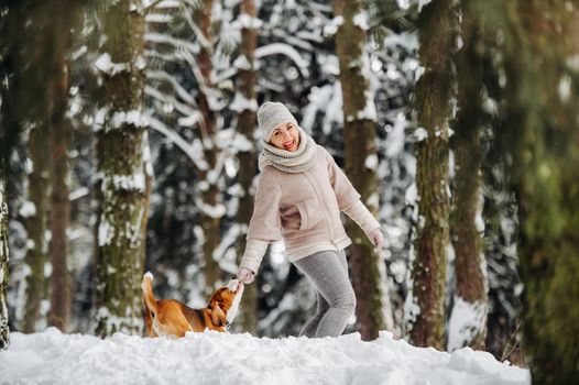 a woman on a walk with her dog in the winter forest. mistress and dog game in the snowy forest.