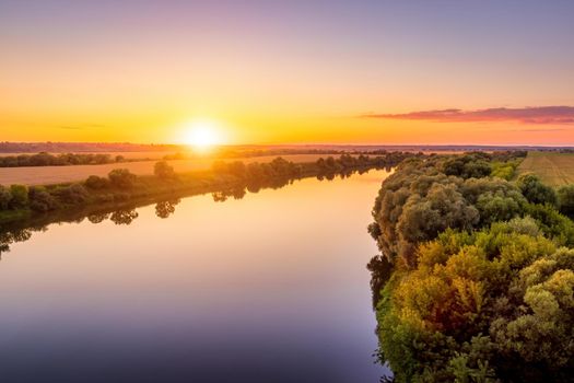 A sunset or sunrise scene over a lake or river with skies reflecting in the water on a summer evening or morning. Landscape.