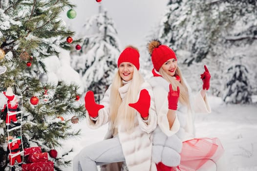 Two girls in the winter forest near a decorated Christmas tree.Girls on a Christmas tree in a snowy forest.
