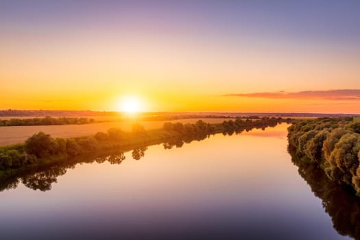 A sunset or sunrise scene over a lake or river with skies reflecting in the water on a summer evening or morning. Landscape.