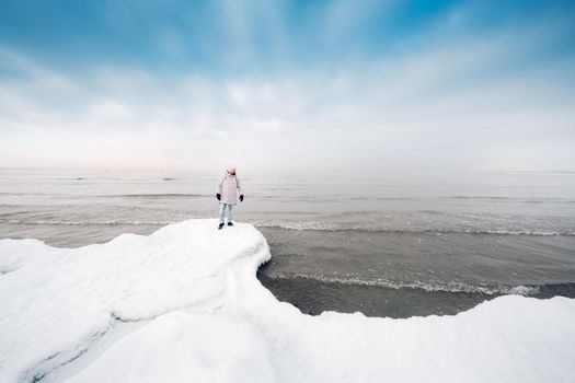 A tourist stands on the shore of the Baltic sea in winter. Winter near the Baltic States of Tallinn.Traveler near the sea in winter