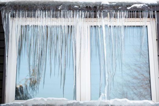 Icicles on the window of the house on a frosty day..