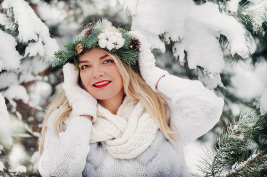 PPortrait of a woman in white clothes in a cold winter forest. Girl with a wreath on her head in a snow-covered winter forest.