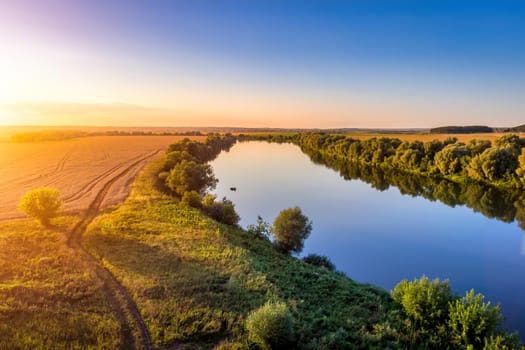 A sunset or sunrise scene over a lake or river with skies reflecting in the water on a summer evening or morning. Landscape.