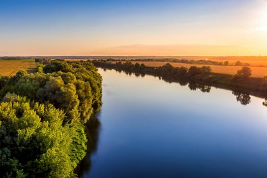 A sunset or sunrise scene over a lake or river with skies reflecting in the water on a summer evening or morning. Landscape.