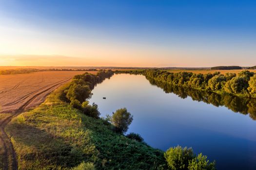 A sunset or sunrise scene over a lake or river with skies reflecting in the water on a summer evening or morning. Landscape.