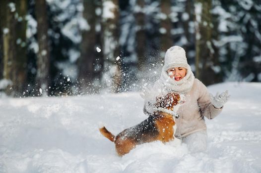 a woman on a walk with her dog in the winter forest. mistress and dog game in the snowy forest.
