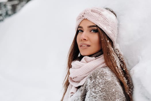 A girl in a sweater and mittens in winter stands on a snow-covered background.