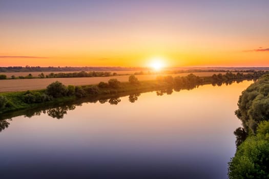 A sunset or sunrise scene over a lake or river with skies reflecting in the water on a summer evening or morning. Landscape.