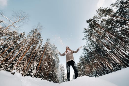 A girl in a sweater and mittens in winter stands on a snow-covered background.