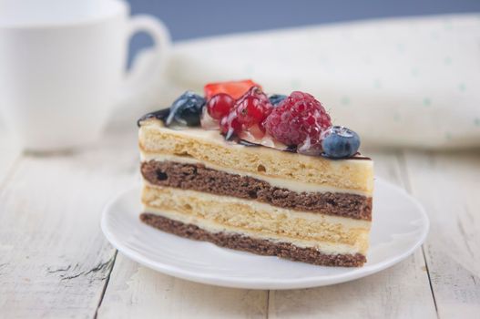 Mix berry colorful slice cake on white plate on wood background