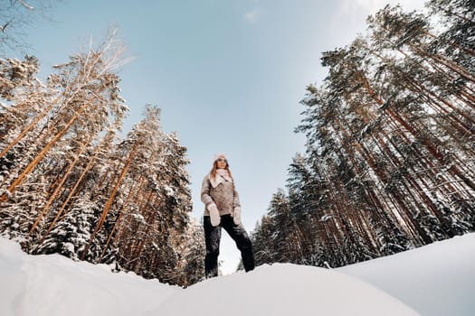 A girl in a sweater and mittens in winter stands on a snow-covered background.