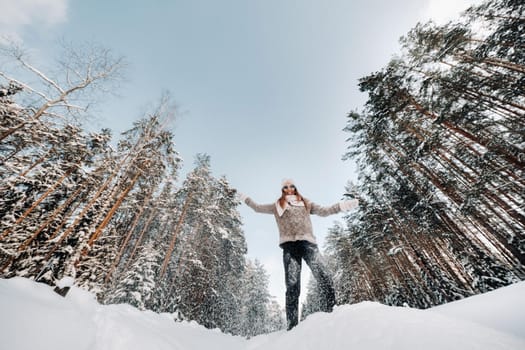 A girl in a sweater and mittens in winter stands on a snow-covered background.