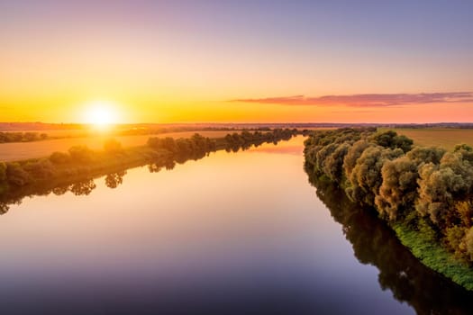 A sunset or sunrise scene over a lake or river with skies reflecting in the water on a summer evening or morning. Landscape.