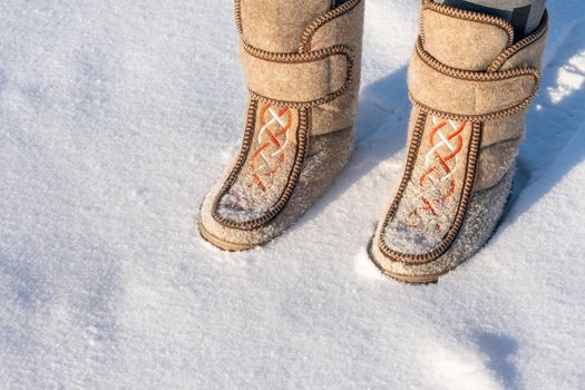 Close-up of a man in felt boots standing in the snow.