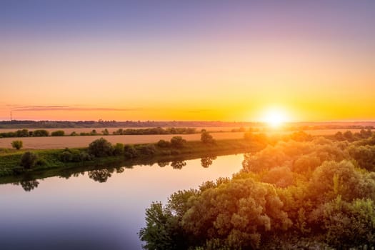 A sunset or sunrise scene over a lake or river with skies reflecting in the water on a summer evening or morning. Landscape.