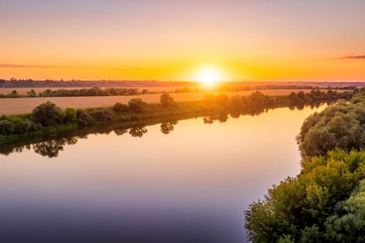 A sunset or sunrise scene over a lake or river with skies reflecting in the water on a summer evening or morning. Landscape.