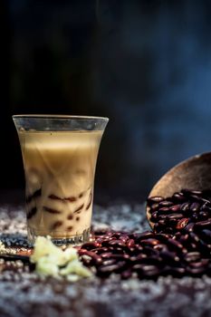 Red bean bubble tea in a glass along with some raw kidney beans, butter and sugar on the brown surface with Rembrandt light technique. Vertical shot.