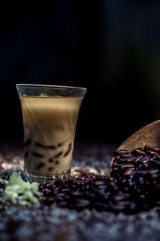 Red bean bubble tea in a glass along with some raw kidney beans, butter and sugar on the brown surface with Rembrandt light technique. Vertical shot.