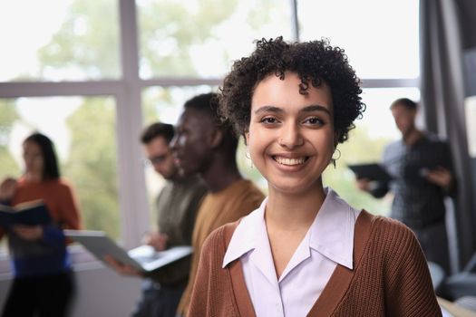 Successful businesswoman standing in creative office and looking at camera while smiling