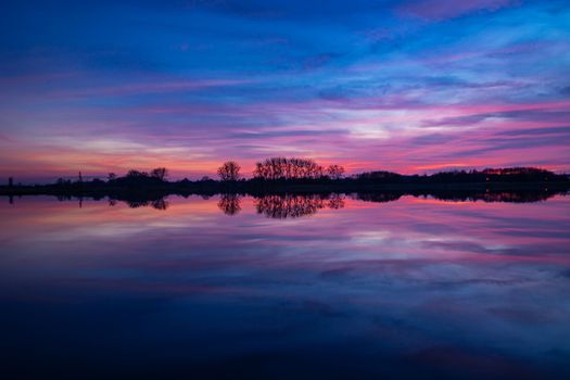 Colorful clouds after sunset and reflection in the lake water