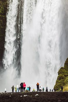 Famous Skogafoss waterfall on Skoga river.Crowds of tourist standing under the waterfall. Iceland, Europe. Landscape photography. High quality photo