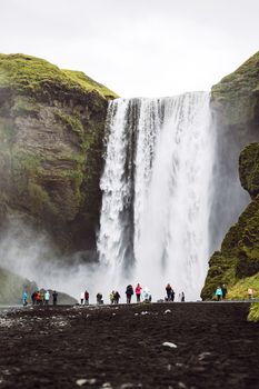 Famous Skogafoss waterfall on Skoga river.Crowds of tourist standing under the waterfall. Iceland, Europe. Landscape photography. High quality photo