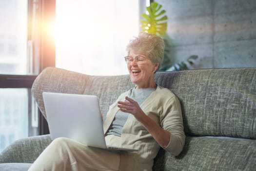 Woman using laptop while sitting on sofa in living room at home