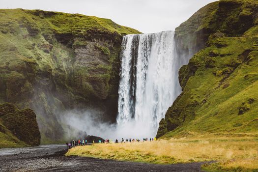 Famous Skogafoss waterfall on Skoga river.Crowds of tourist standing under the waterfall. Iceland, Europe. Landscape photography. High quality photo