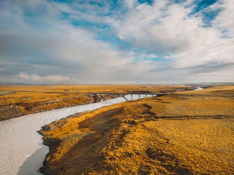 Bright blue river running under a bridge trough Iceland mainland in autumn time on a cold day. High quality photo