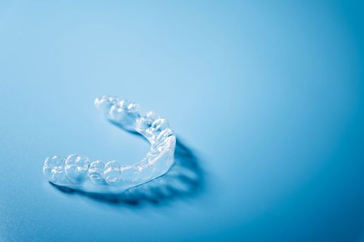 Close up invisible aligners on the blue background with copy space. Plastic braces dentistry retainers to straighten teeth.