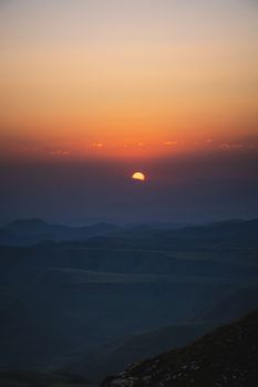 Beautiful mountain landscape with sunset over the mountains from the top of the mountain. Photo in orange-blue natural tones.