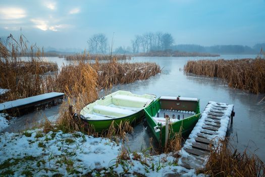 Small boats on the shore of a frozen lake