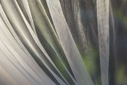 Close-up of a white and wrinkled mesh curtain in the window