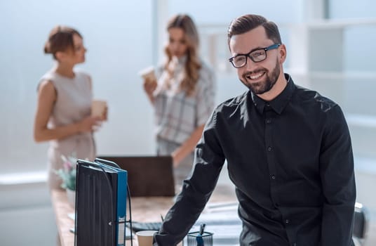 smiling young businessman standing in office. business concept